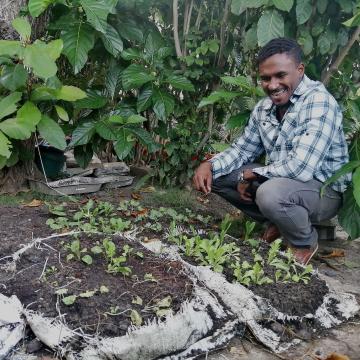 SOIL’s Director of Operations, Djimitri Célestin, growing directly out of Konpòs Lakay bags mixed with soil.